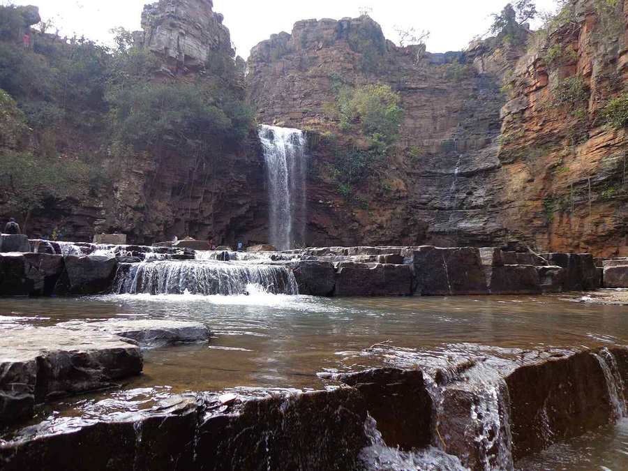 Milky tiers of water dropping over rock ledges at Tirathgarh Falls
